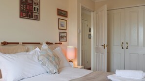 A neatly made bed with pillows and a blanket, a bedside lamp, and a set of towels on the floor. - 2 bedroom accommodation in Chivenor Cross, near Barnstaple (Chivenor Cross, near Barnstaple)