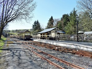 A railway station with tracks, a waiting platform, and a small building.