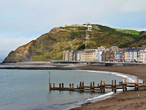 A coastal town with a prominent hill, a pier, and a row of colorful buildings.