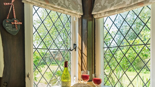 A window with a view of greenery, a bottle of wine, a loaf of bread, and a plate of grapes. - 2 bedroom accommodation in Eckington, near Pershore (Eckington, near Pershore)