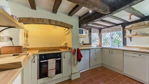 A kitchen with white cabinets, a wooden countertop, a built-in oven, and a window with a view of greenery. - 2 bedroom accommodation in Eckington, near Pershore (Eckington, near Pershore)