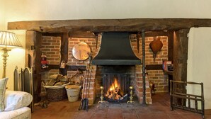A cozy room with a fireplace, a lamp, and a cushioned bench. - 2 bedroom accommodation in Eckington, near Pershore (Eckington, near Pershore)