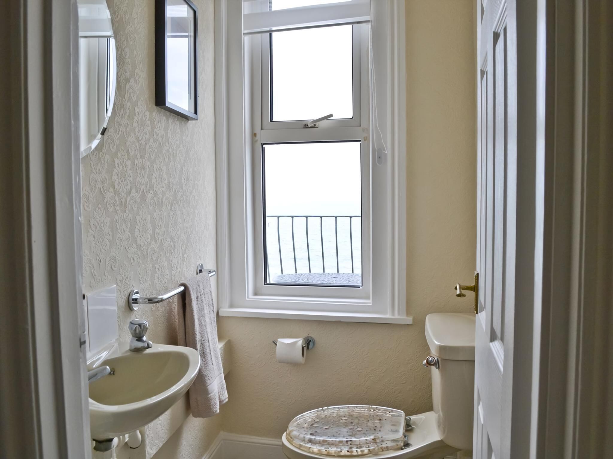 A bathroom with a sink, toilet, and window.