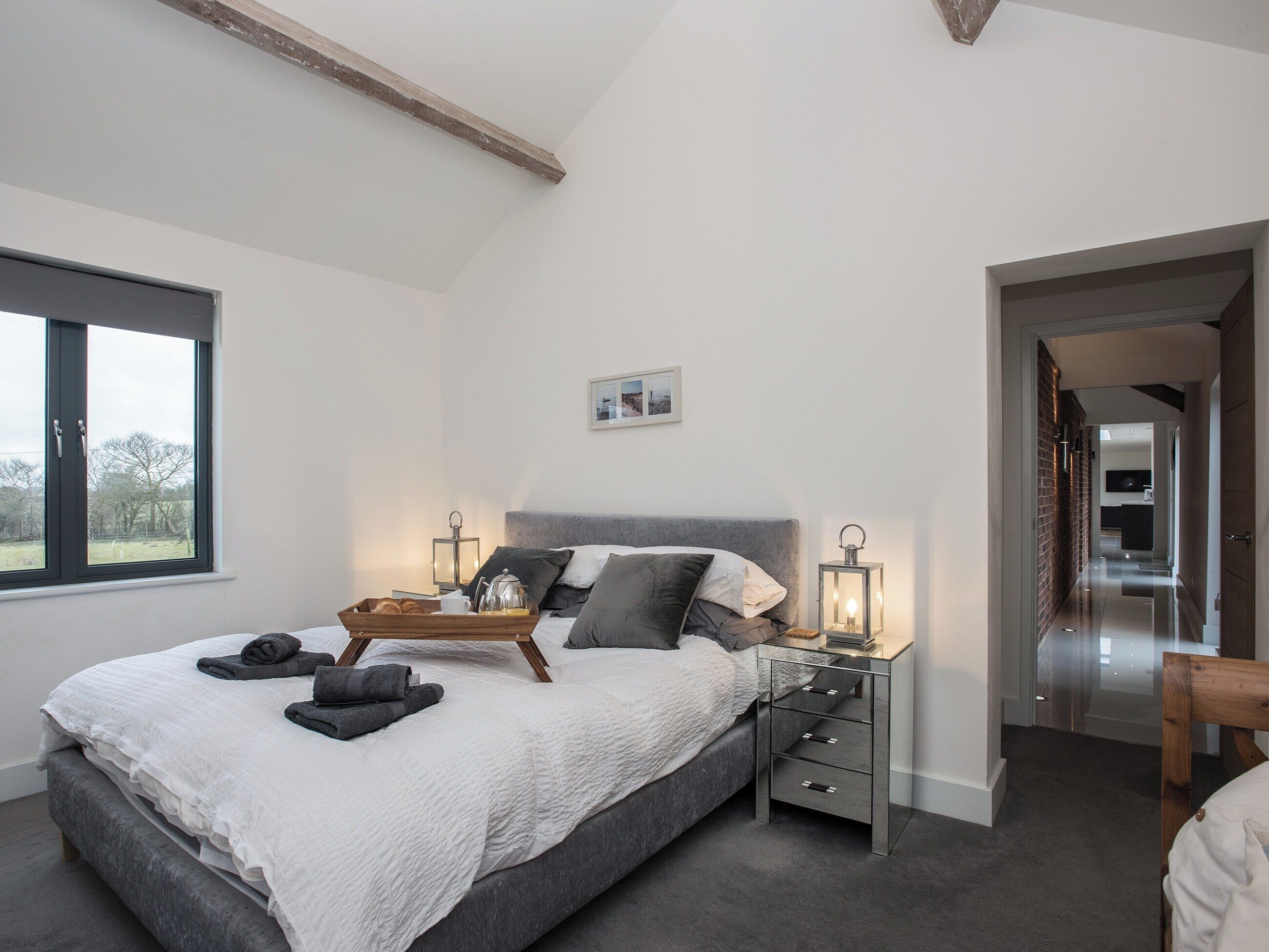 Une chambre à coucher avec un grand lit, des tables de chevet, une fenêtre et une vue sur l’extérieur.