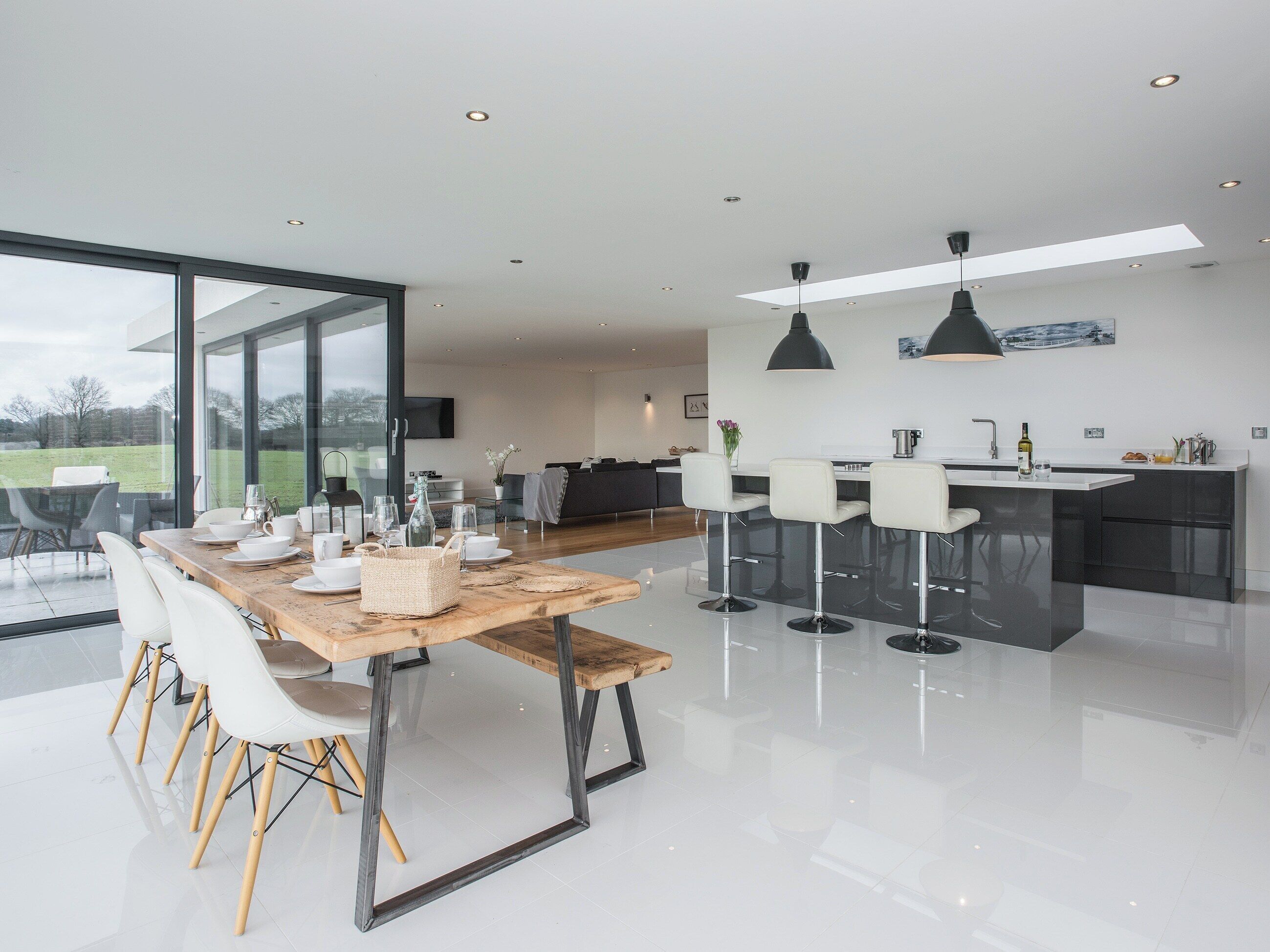 Une cuisine moderne dotée d’un îlot central, de tabourets de bar et d’un coin repas avec une grande table et des chaises.