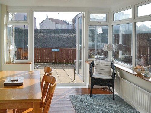 Modern accommodation with sun room and patio overlooking a small lake.