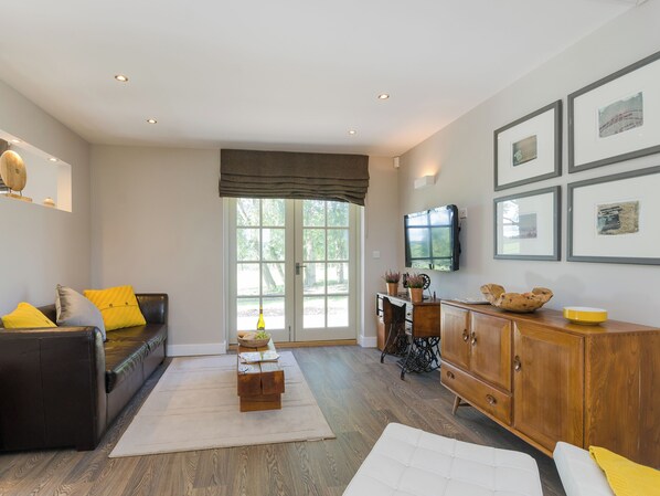 A modern living room with a sofa, a wooden cabinet, a television, and framed pictures on the wall.