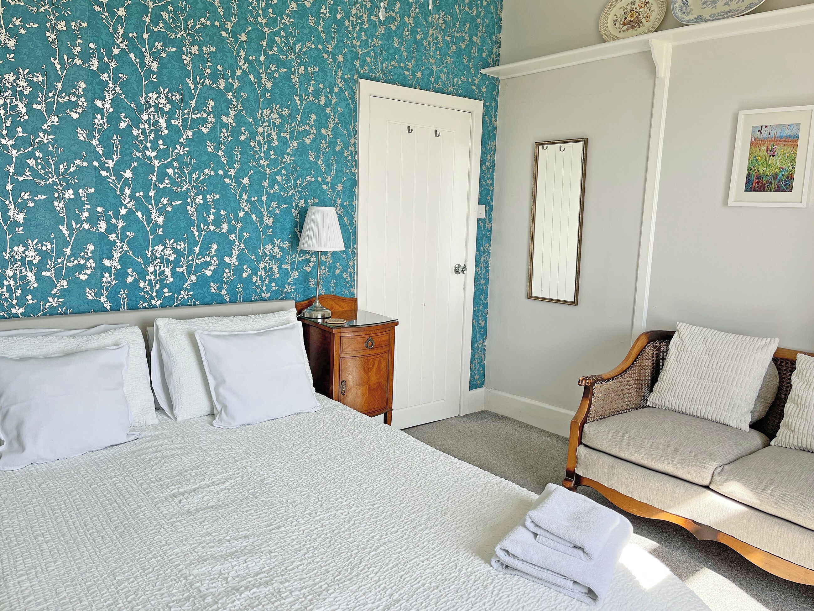 A bedroom with a bed, a nightstand, a dresser, a chair, and a door.