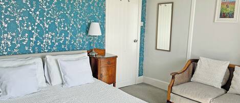 A bedroom with a bed, a nightstand, a dresser, a chair, and a door.