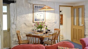 A dining area with a table set for two, a wicker lamp, and a poster on the wall. - 2 bedroom accommodation in Betws-y-Coed (Betws-y-Coed)
