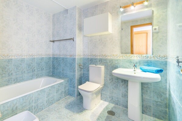 A bathroom with a bathtub, toilet, and sink.