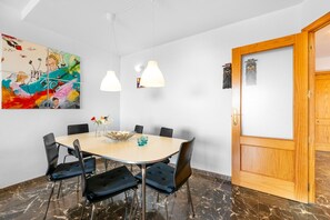 A conference room with a round table, six chairs, a white ceiling, and a wooden door.