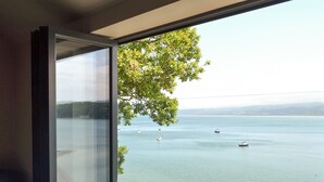 A room with a large window overlooking a calm body of water with boats.