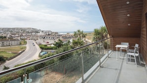 Un balcón con vistas a un pueblo costero, una carretera y una playa.
