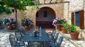 An outdoor dining area with a stone wall, a pergola, and potted flowers. - VILLA CHIANTIVERTINE (Vertine)