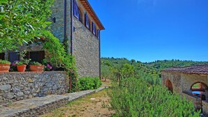 A stone building with a stone pathway leading to a rustic archway. - VILLA CHIANTIVERTINE (Vertine)