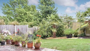 A garden with various potted plants and a wooden fence in the background. - 3 bedroom accommodation in Preston, near Weymouth (Preston, near Weymouth)