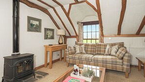 A cozy living room with a fireplace, a plaid sofa, a coffee table with books, and a window with curtains. - 2 bedroom accommodation in Kinross, near Perth (Kinross, near Perth)
