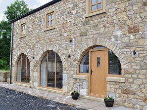 A stone building with arched windows, a wooden door, and a year plaque.