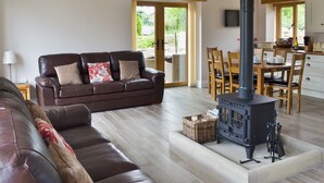 A living room with a sofa, a fireplace, a dining area with chairs and a table, and a kitchen with a TV. - 3 bedroom accommodation in Pendleton, near Clitheroe (Pendleton, near Clitheroe)