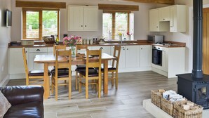A modern kitchen with wooden beams, a dining area with a table and chairs, and a black wood-burning stove. - 3 bedroom accommodation in Pendleton, near Clitheroe (Pendleton, near Clitheroe)