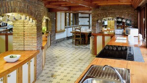 A rustic kitchen with exposed wooden beams, a brick wall, and a tiled floor. - The Farmhouse - UKC1339 (Heasley Mill, near South Molton)