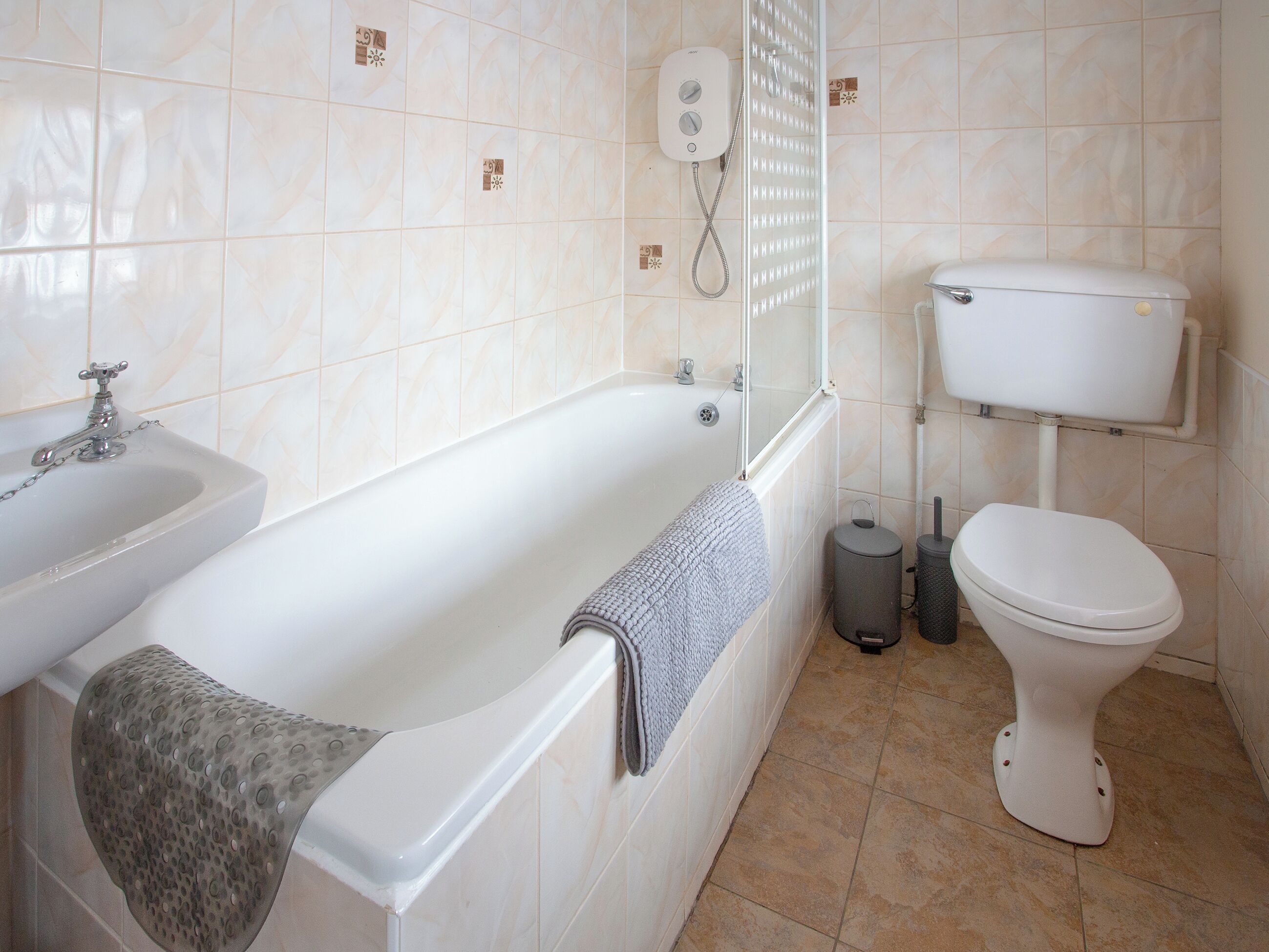 A bathroom with a bathtub, a toilet, a sink, and a shower control panel.