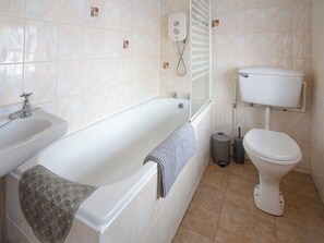 Ein Badezimmer mit Badewanne, Toilette, Waschbecken und Duschsteuerung.