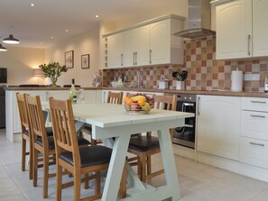 A modern kitchen with white cabinets, a tiled backsplash, and a central island with a fruit bowl.