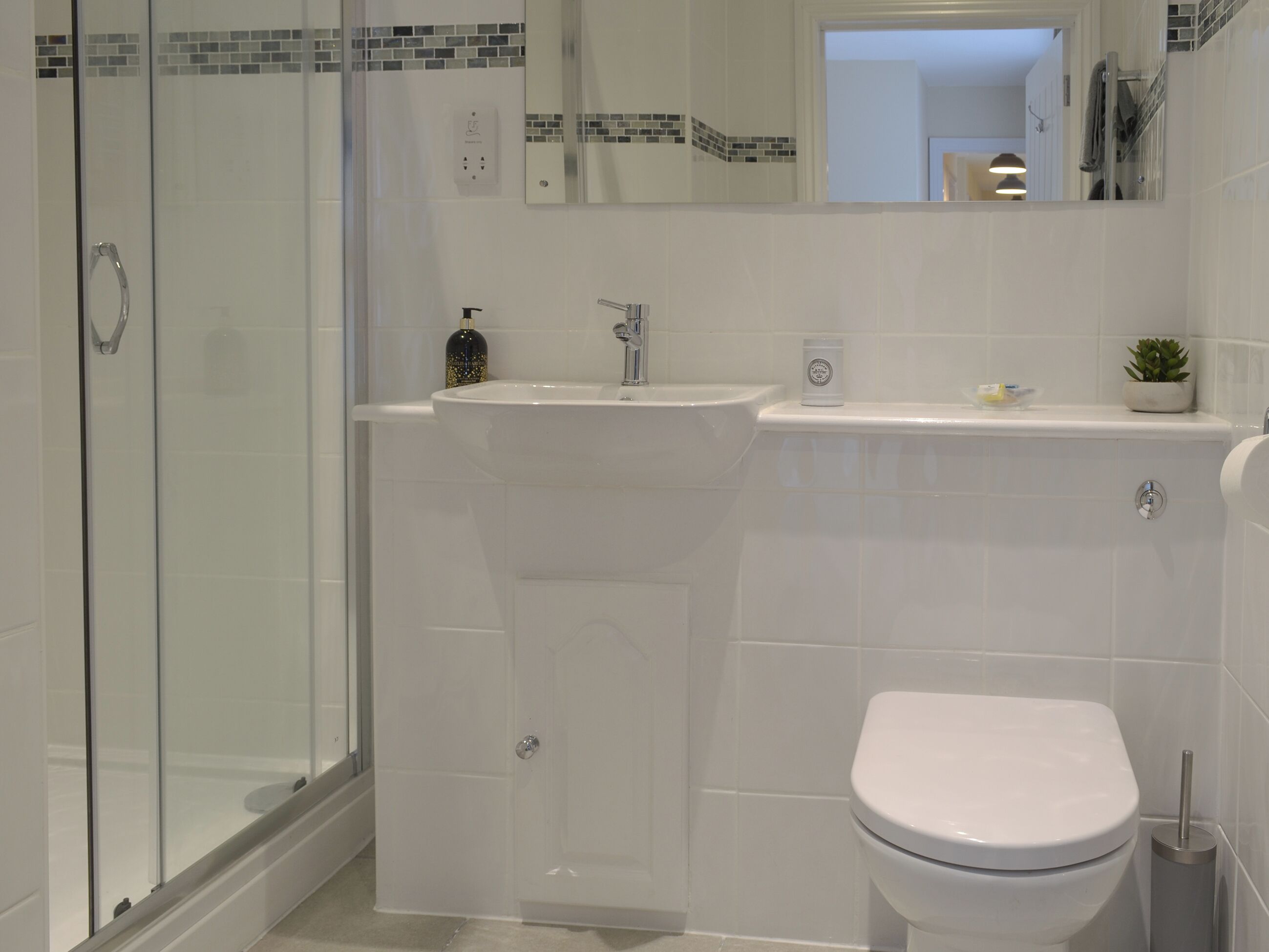 Une salle de bain moderne avec une douche à parois de verre, un lavabo blanc et des toilettes.