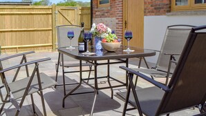 An outdoor patio with a round table, two chairs, and a vase with flowers. - Woodlands Dairy Cottage (Adversane, near Billingshurst)