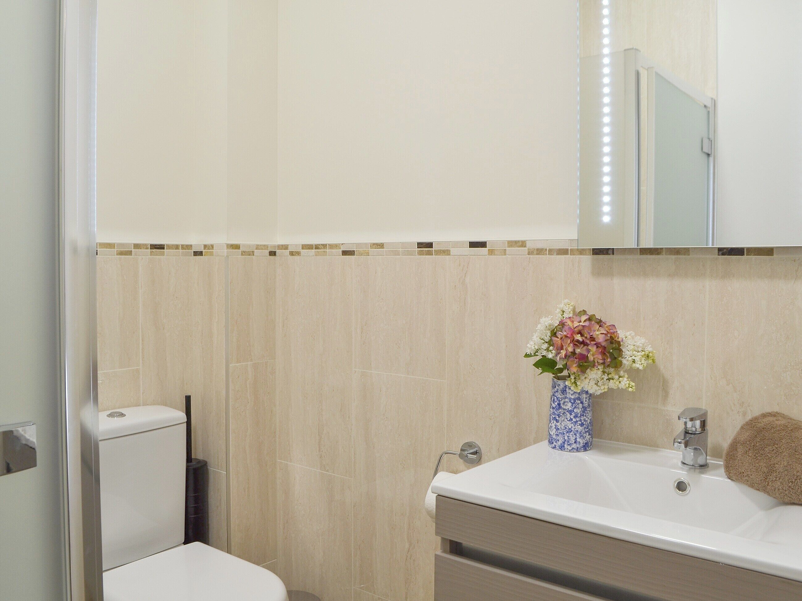 A bathroom with a toilet, sink, and mirror.