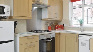 Une cuisine avec des meubles de rangement en bois, une cuisinière à gaz, un four à micro-ondes et un grille-pain.