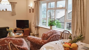 A cozy living room with a fireplace, a television, and a dining area set for a meal. - 2 bedroom accommodation in Kentmere, near Staveley (Kentmere, near Staveley)