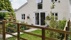 Ein zweistöckiges Haus mit Eingangstür, Fenstern und einem Holzzaun.