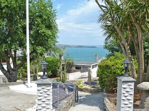 Un sentier côtier bordé de garde-corps en pierre, un lampadaire et une vue sur la mer.
