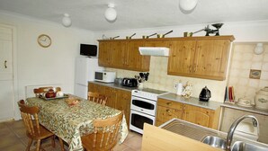 A kitchen with wooden cabinets, a microwave, an oven, and a sink.