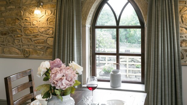 A dining table set with plates, a vase with flowers, and a wine glass. - 2 bedroom accommodation in Alton, near Chesterfield (Alton, near Chesterfield)