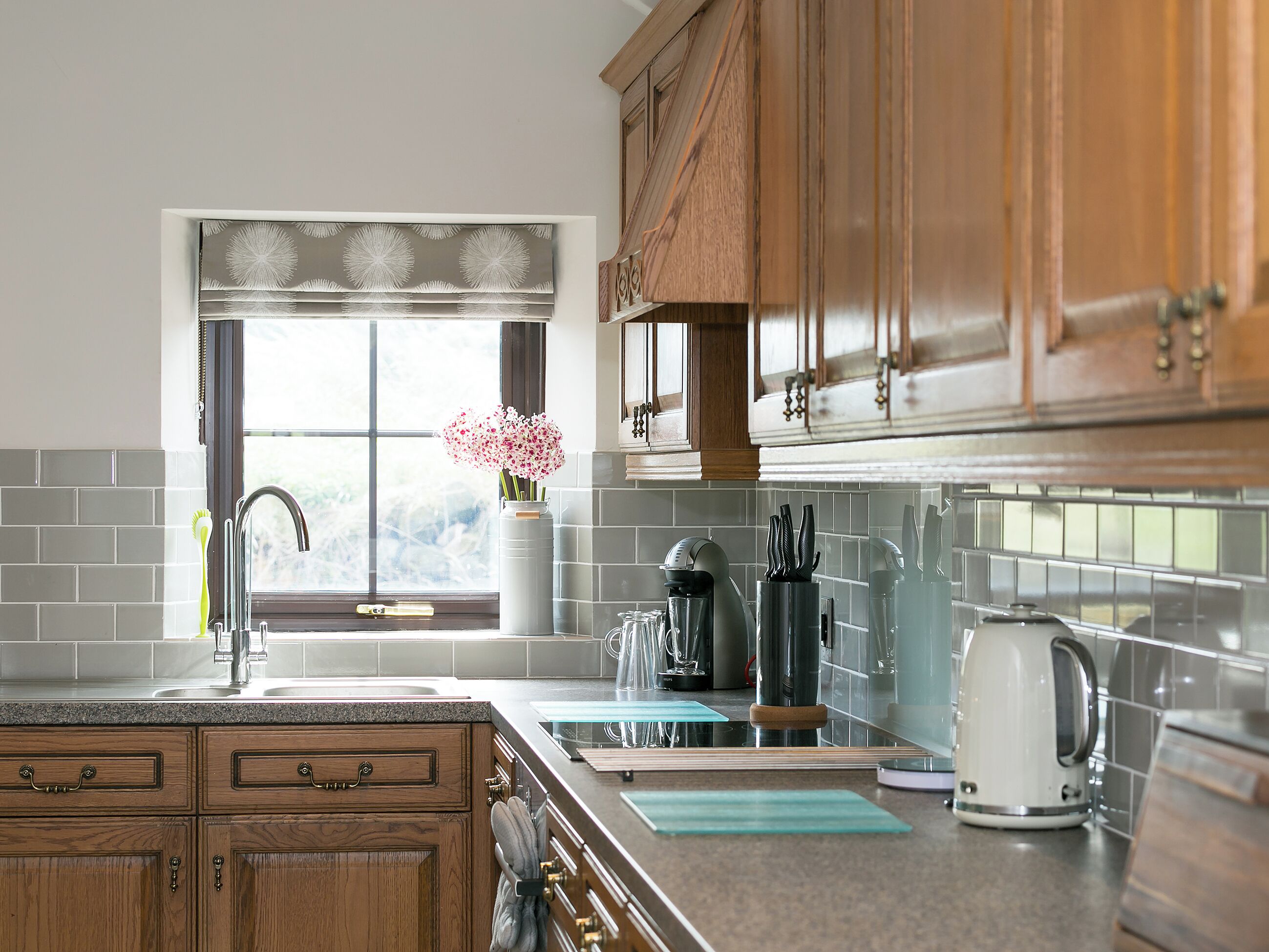 A kitchen with wooden cabinets, a window with a view, a sink, and various kitchen appliances.