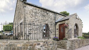 A stone building with a wooden door, a small porch, and a metal fence. - 2 bedroom accommodation in Alton, near Chesterfield (Alton, near Chesterfield)