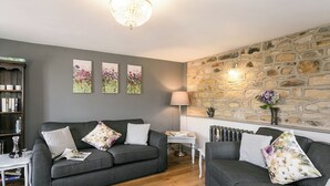 A living room with two grey sofas, a white rug, a stone wall, and a chandelier. - 2 bedroom accommodation in Alton, near Chesterfield (Alton, near Chesterfield)