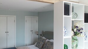 A bedroom with a bed, a wardrobe, and a shelf with decorative items. - 1 bedroom accommodation in Turville, near Henley-on-Thames (Turville, near Henley-on-Thames)