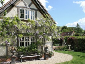 A traditional house with a garden, a gravel driveway, and a bench.