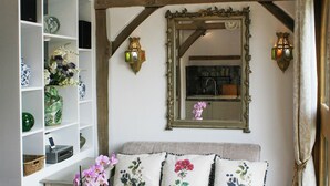 A cozy room with a sofa, decorative pillows, a mirror, and wall-mounted lights. - 1 bedroom accommodation in Turville, near Henley-on-Thames (Turville, near Henley-on-Thames)