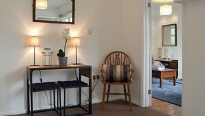 Una habitación con una consola, dos lámparas, un espejo, una silla y un escritorio con otra silla.