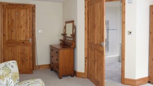Une pièce avec des portes en bois, une commode dotée d’un miroir et une chaise à motifs floraux.