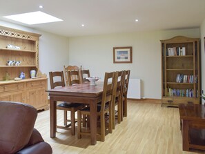 Un coin repas avec une table et des chaises en bois, une bibliothèque et un radiateur.