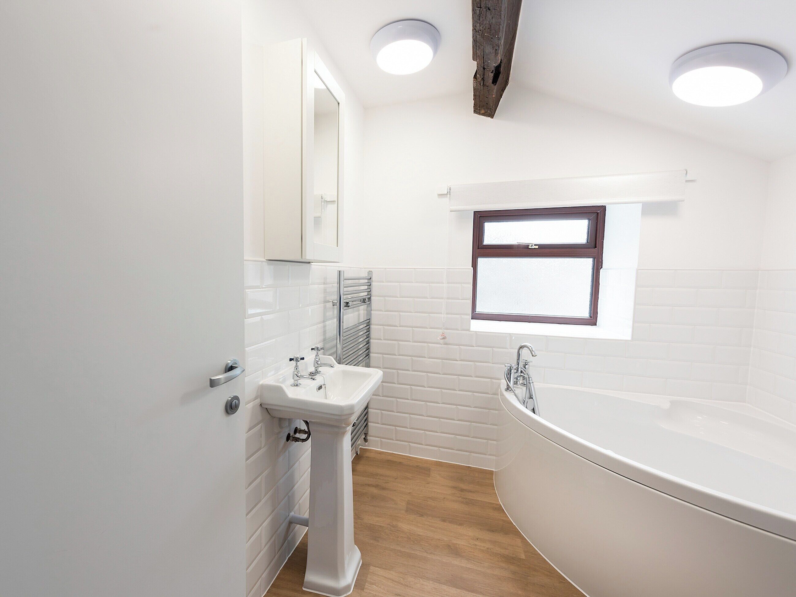 Ein modernes Badezimmer mit Waschbecken, Badewanne und Fenster.