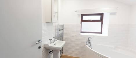 Ein modernes Badezimmer mit Waschbecken, Badewanne und Fenster.