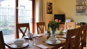 Comedor con una mesa dispuesta para cuatro, un televisor y una pared con una cita inspiradora.